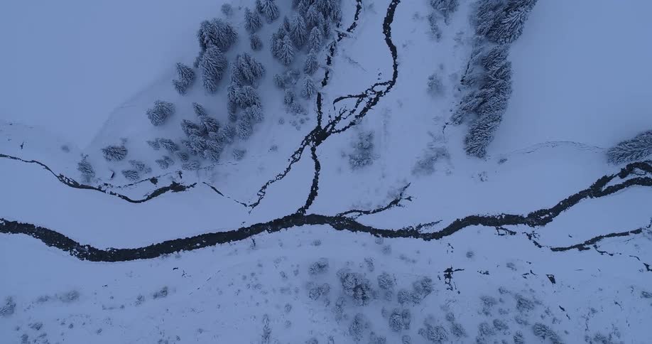 Top down aerial view of a branching river winding down a snow covered landscape