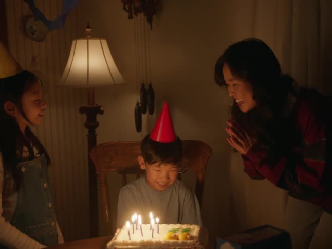 Happy family celebrating a birthday with a cake at home