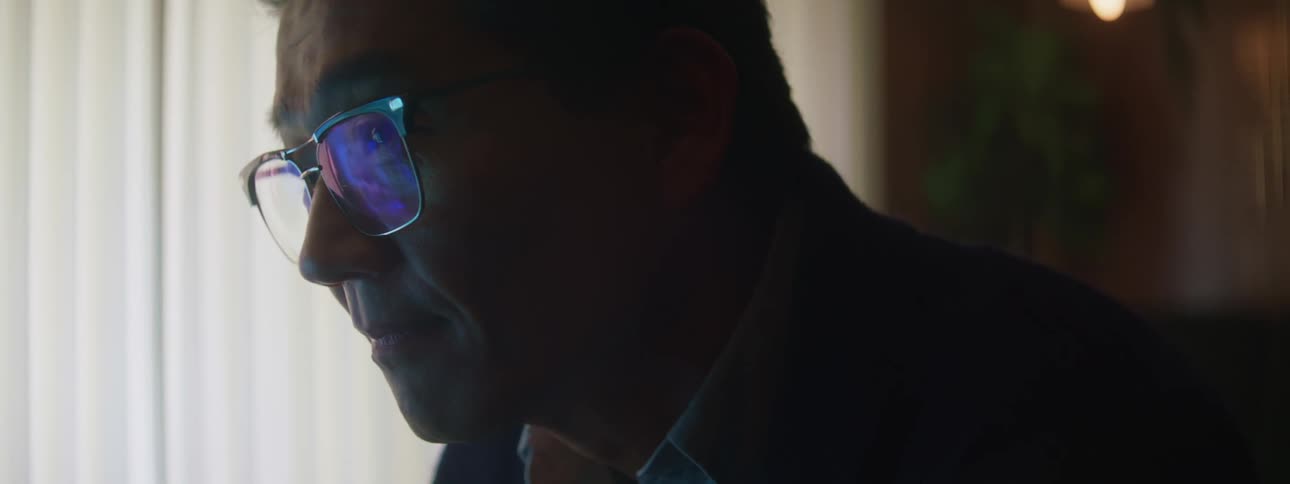 A man in glasses relaxing and watching television