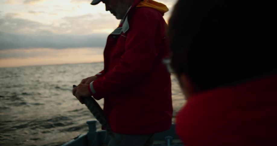 Family wearing bright red jackets sitting on a boat on a fishing trip