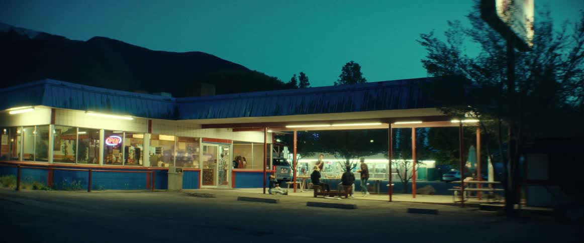 A group of teens hanging out outside of a diner