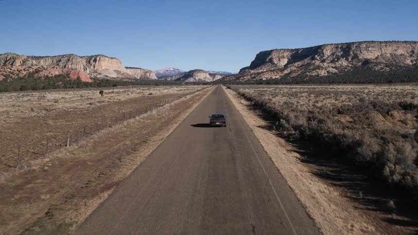 A car is traveling down a deserted road