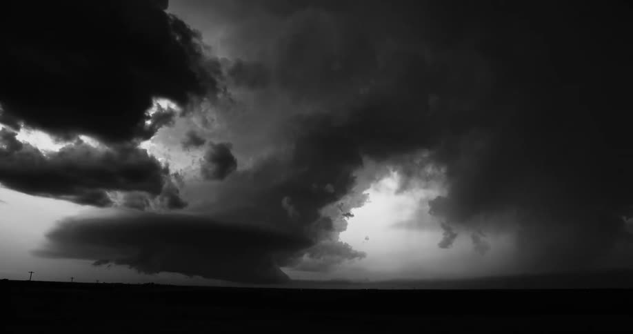 Lightning flashes as it strikes as dark storm clouds move over rural land
