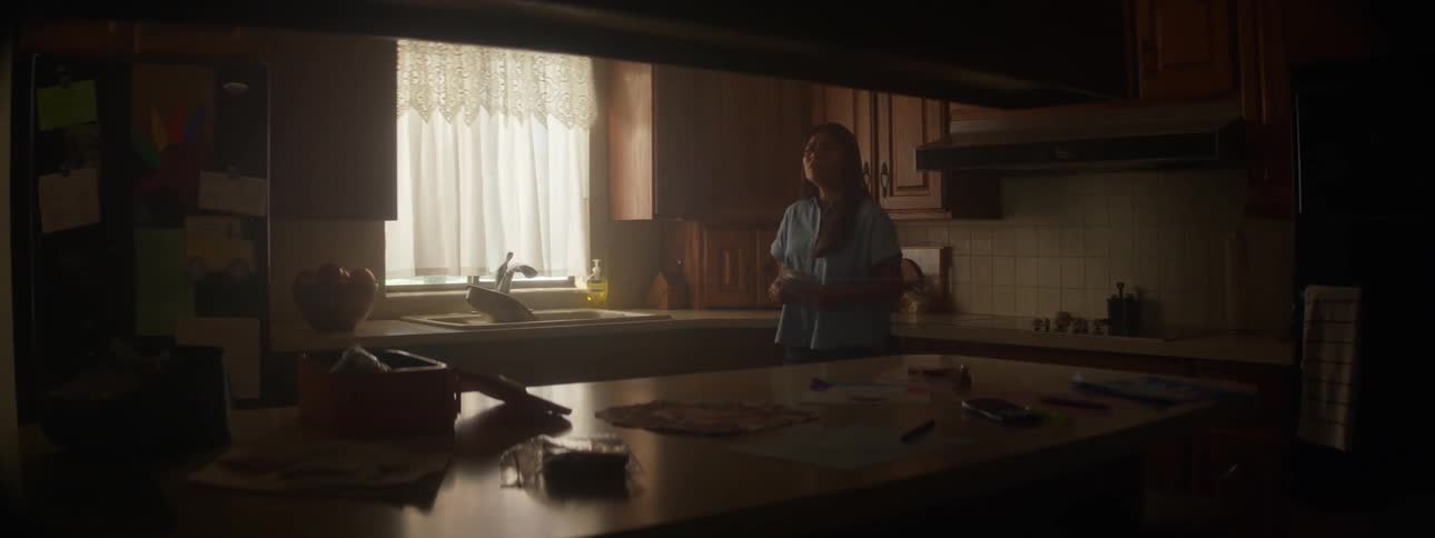 Mother looking at letters in the kitchen talks to boys running in the house