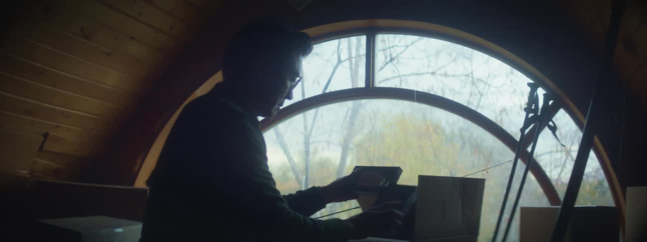 Man wearing glasses and shirt opens box and checking personal belongings in the attic