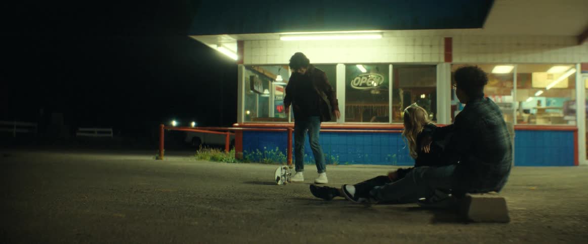 A teenage boy attempts a skateboard trick while his friends watch