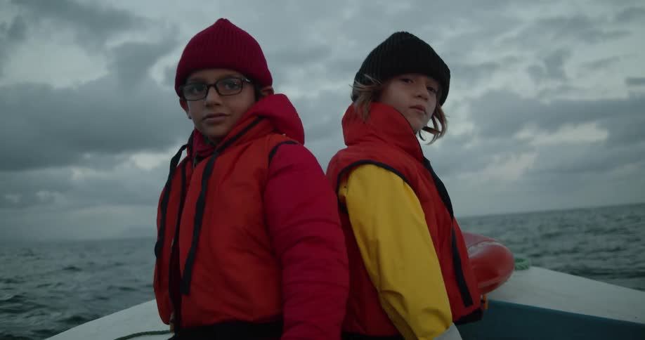 Two boys wearing hats and life jackets on a boat