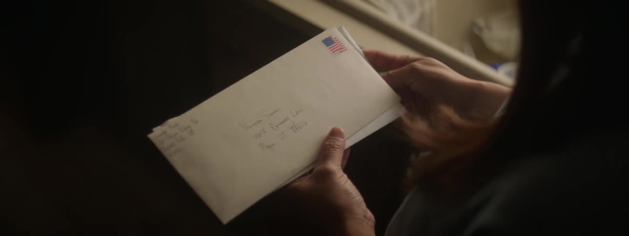 A person is standing indoors and looking through mail