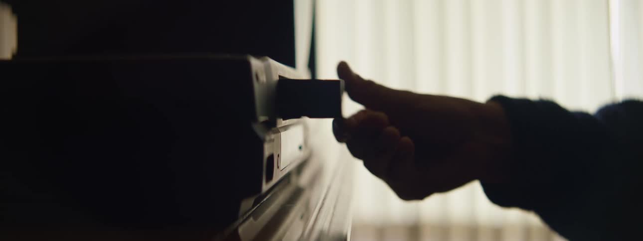 Someone reaches over and puts a vhs tape into the vcr video player