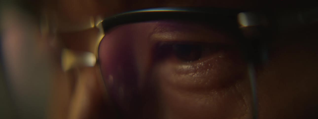 Close up of the eyes of a man wearing glasses inside a room