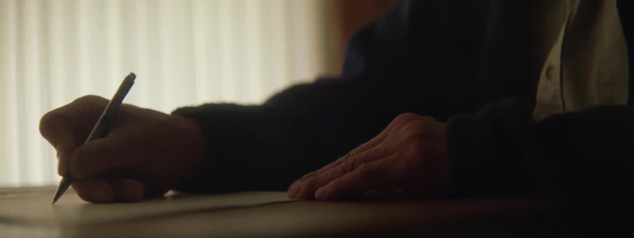 Elderly person writing a letter with a pen and paper