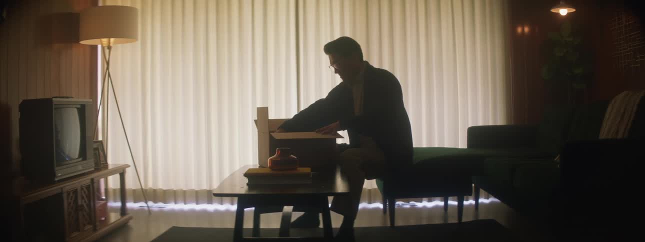 Man sitting on the living room at home opens a cardboard box