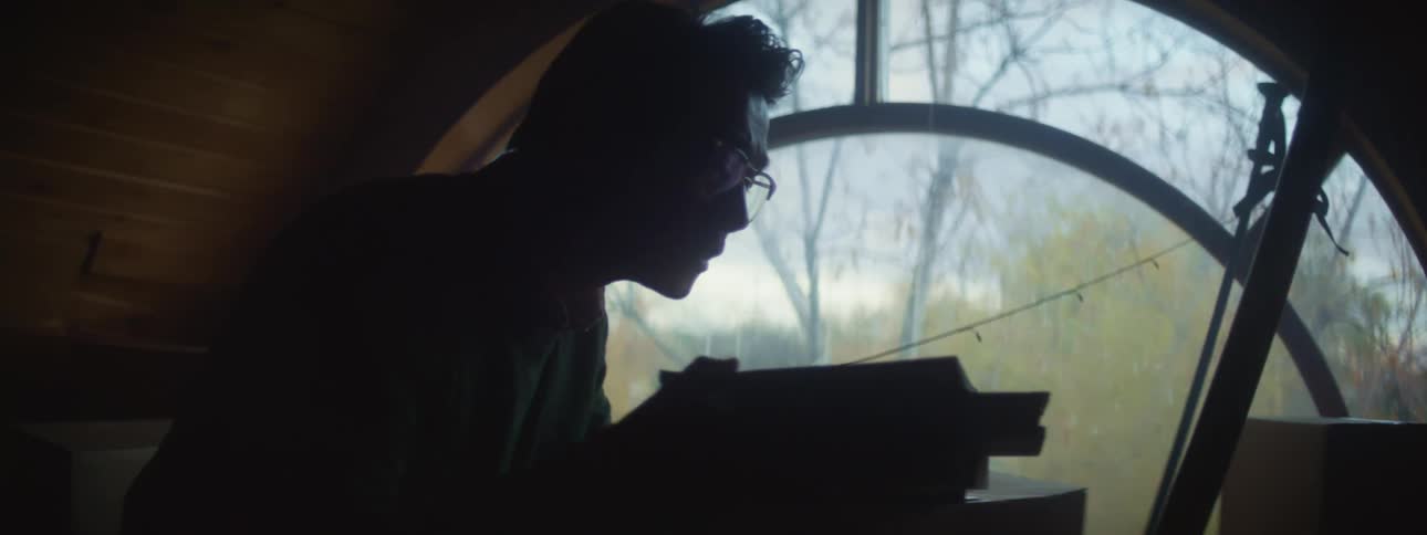 Silhouette of a man dusting off books in the attic