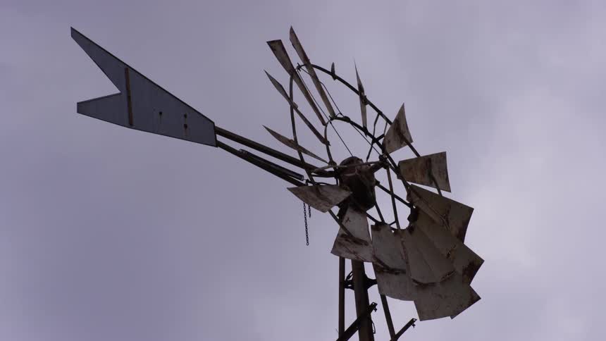 A broken down windmill is in a cloudy sky