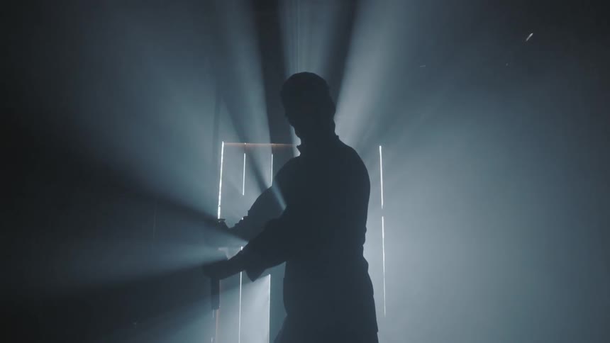 Man holding a sword standing in a dark room