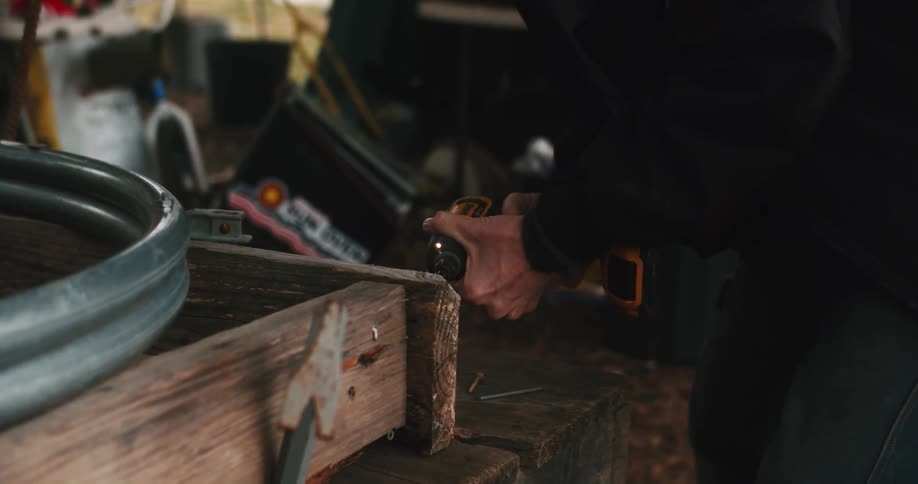 Farmer uses a drill to build something for the farm