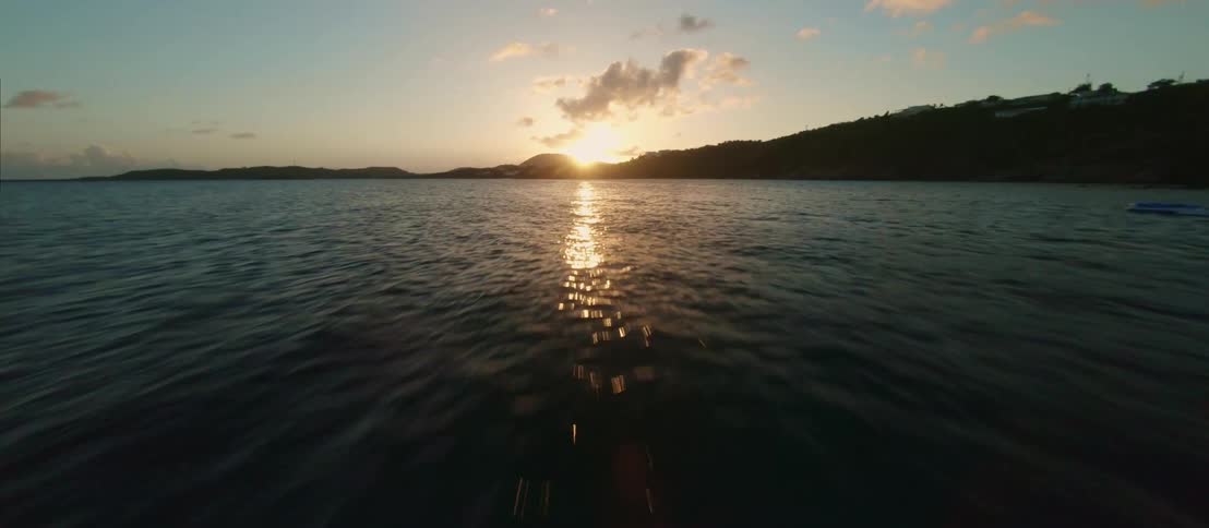 FPV - Aerial view of sailboats floating on the calm ocean surface at sunse