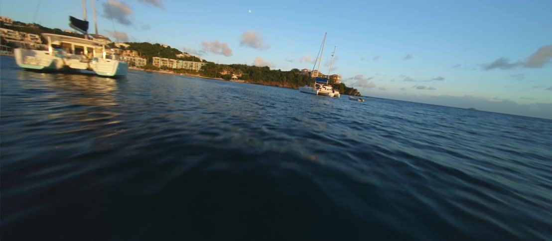FPV - Boats on the ocean anchored near the coastline and an aerial view of the ocean