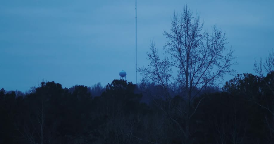 A tall antenna is near the water tower