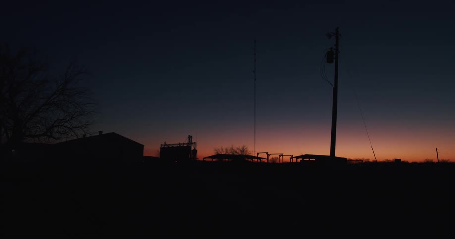 Silhouette of small rural buildings in the countryside under a red sky at sunset