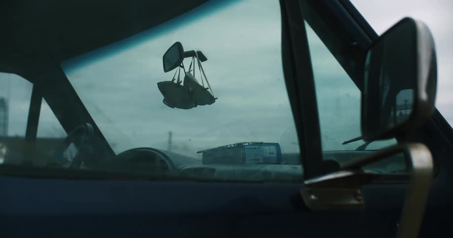 Masks hanging over the dashboard of a car from the rearview mirror on the windhsield