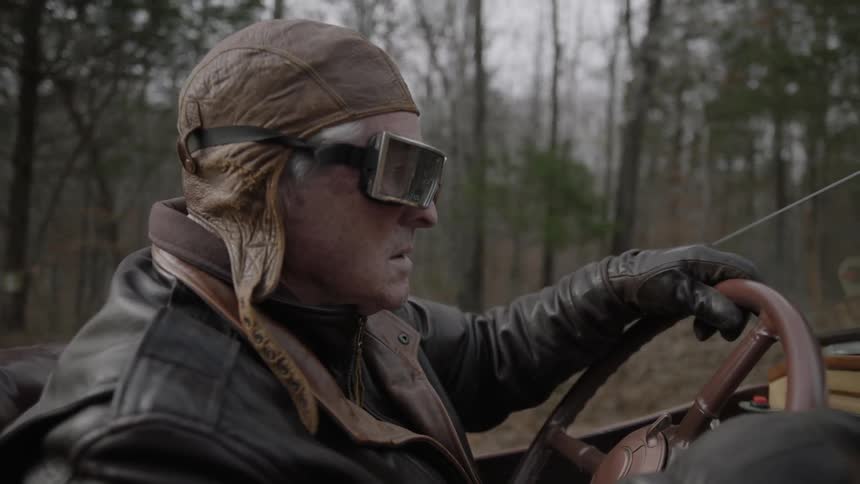 A man is driving a vehicle past a forest