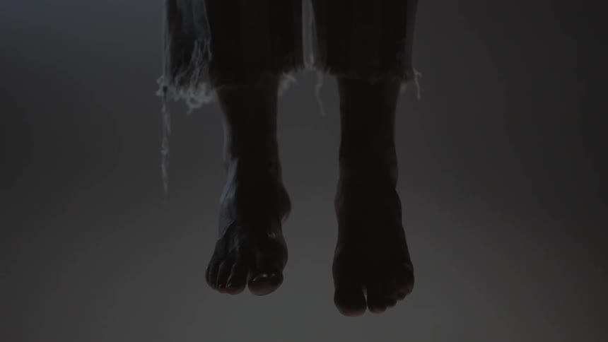 A pair of feet sway in a dark room