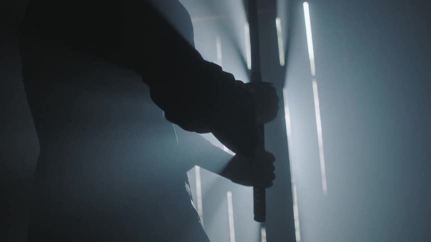 A man holds a stick by a closed door