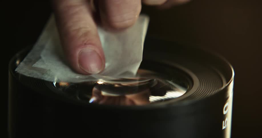 Closeup of hand cleaning camera lenses with microfiber cloth