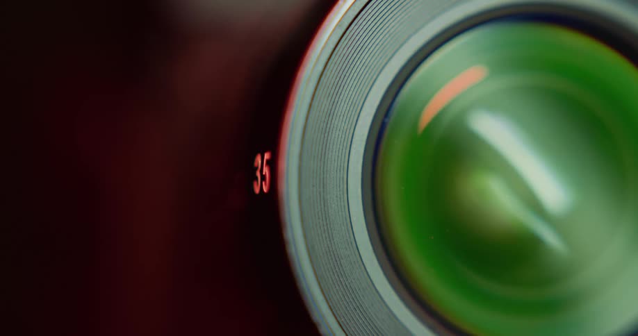Extreme close up of the lens of a photography camera under red lights