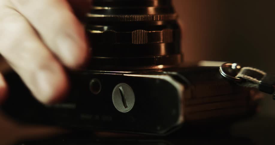 Close up of a vintage photography camera being picked up by a hand