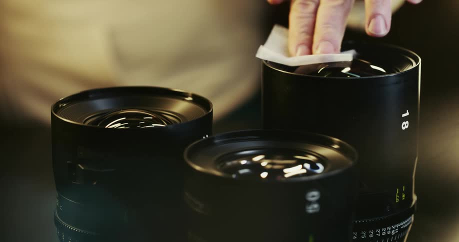 Person cleans camera lenses using micro fiber cloth