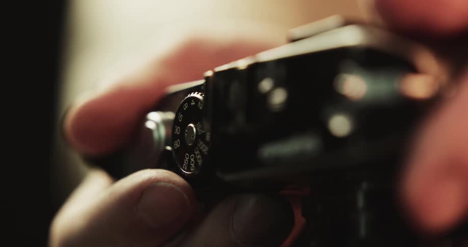 Close up of a person using his thumb to turn a lever on a vintage photography camera