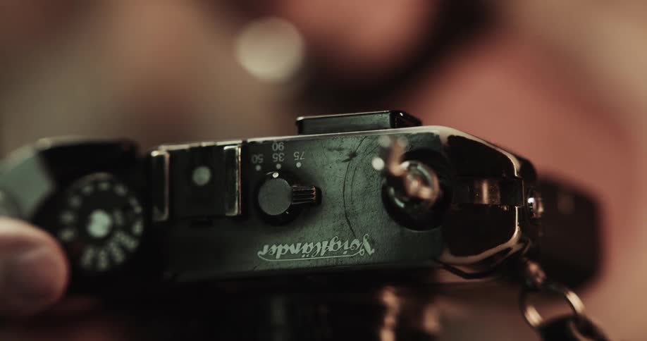 Someone is holding an old camera in their hands and opening the back