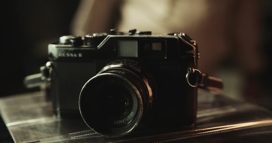 Close up of a person placing a vintage camera over a reflective surface