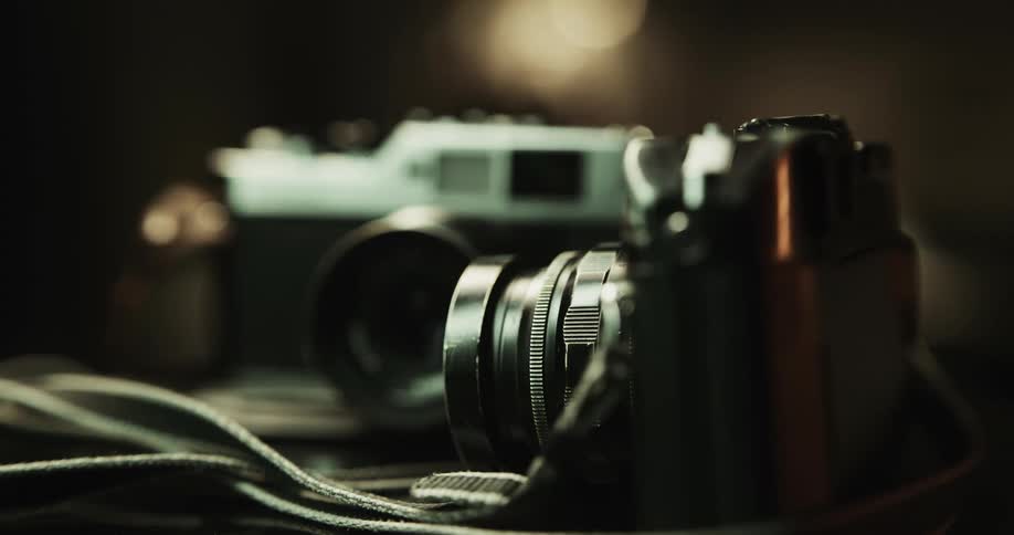 Two vintage photography cameras resting on a desk inside a room