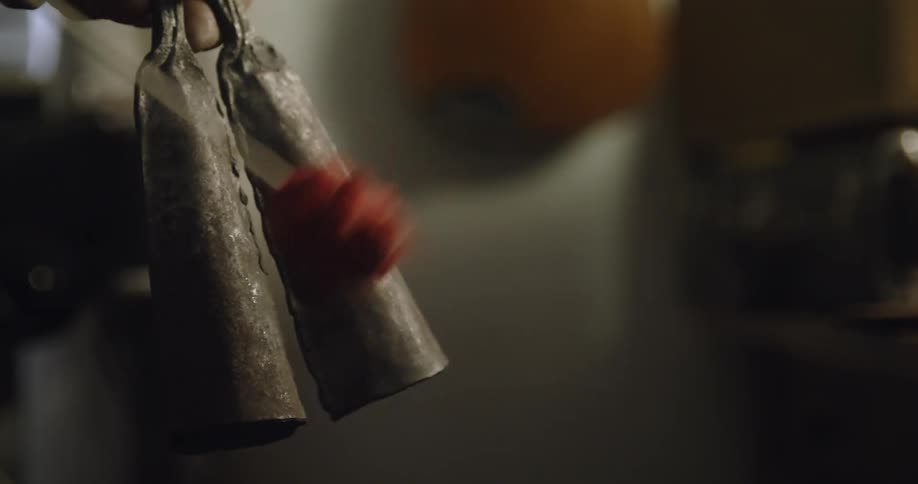 Close up of a musician playing double cowbells on a room