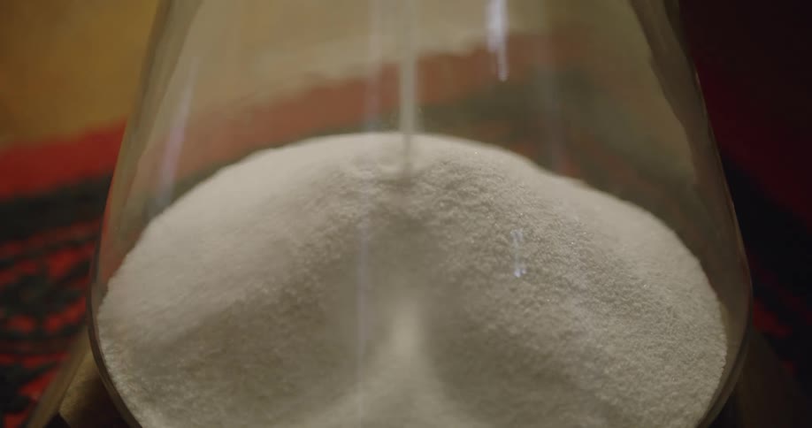Salt being poured into a glass jar on counter