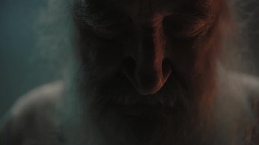 An old bearded man is looking down