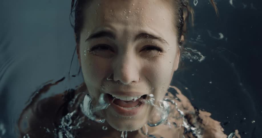 Close up of air bubbles escaping the mount of a screaming woman submerged underwater