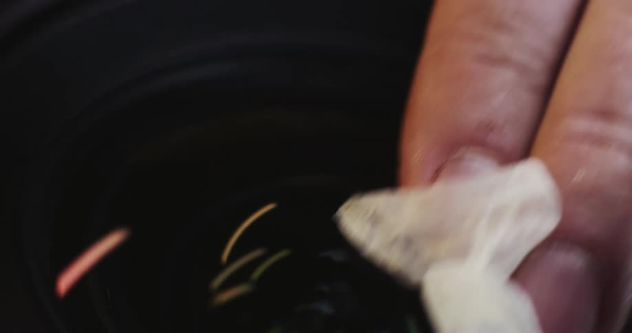 Closeup of hand cleaning camera lenses with rag