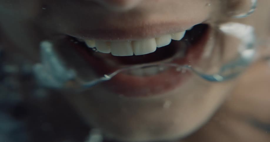 Close up of air bubbles escaping the mount of a screaming woman submerged underwater
