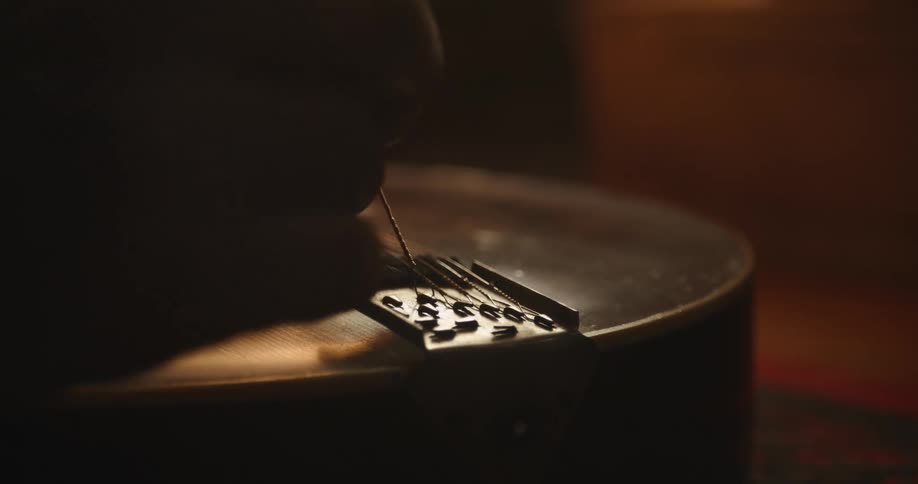 Close up view of a person fixing a guitar string is displayed