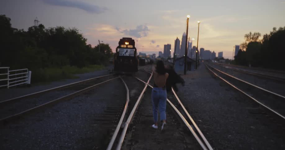 A woman walks between train tracks near downtown