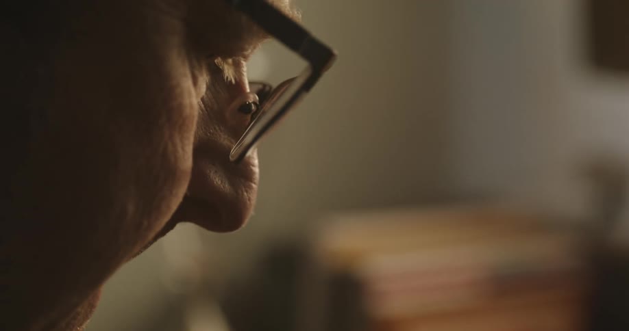 Close view of the head of a man sitting at a desk indoors while looking down and focused on doing something