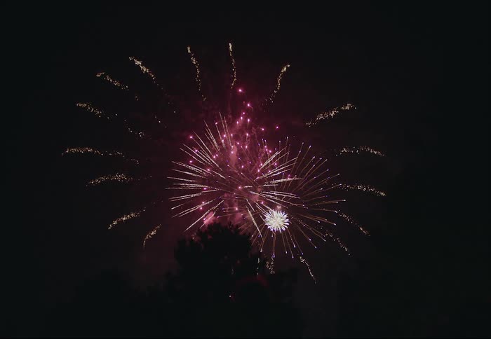 Colorful fireworks glow in the darkness as they explode across the night sky