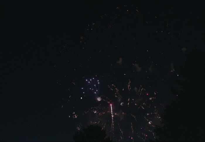 Colorful fireworks glow in the darkness as they explode across the night sky