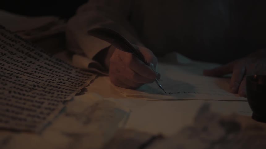 A man uses a quill to write with