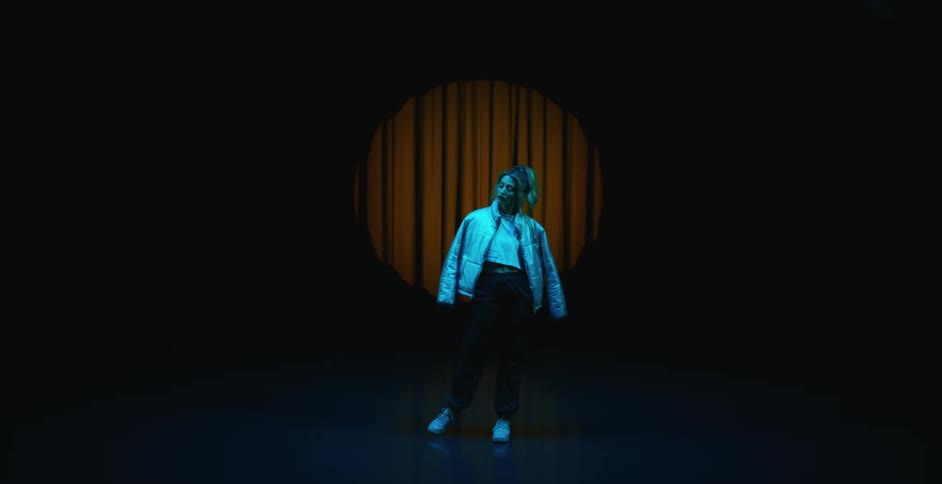 A woman wearing a white coat standing moving around slowly