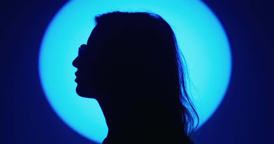 A woman is standing in a room and wearing glasses